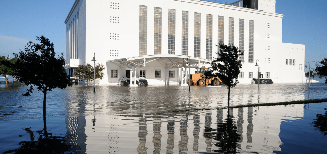 Floodwater surrounds buildings and vehicles after heavy flooding, a scene relevant to a property insurance claim.